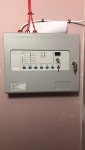 Fire-alarm-mounted-on-pink-wall